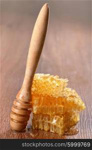 honeycombs and drizzler on wooden background