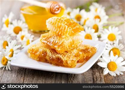 honeycombs with daisy flowers on wooden table