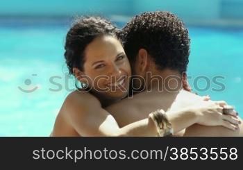 Honeymoon: happy young newlyweds hugging and relaxing near hotel pool