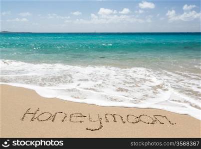 Honeymoon words written into sand on beach by sea in St Thomas
