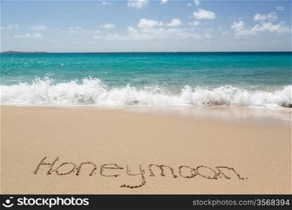 Honeymoon words written into sand on beach by sea in St Thomas