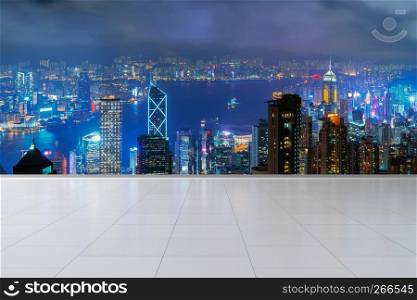 Hong Kong City and Victoria Harbour with tiles flooring. Financial district in downtown and business centers in smart urban city in Asia. Skyscraper and high-rise buildings at night.