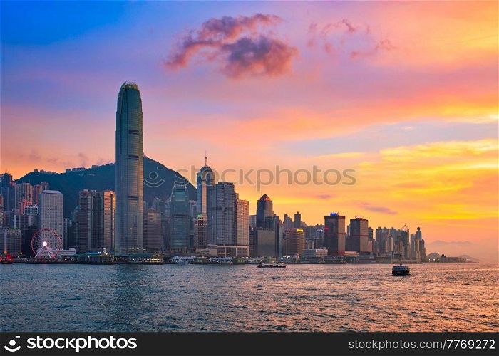 Hong Kong skyline cityscape downtown skyscrapers over Victoria Harbour in the evening with junk tourist ferry boat on sunset with dramatic sky. Hong Kong, China. Junk boat in Hong Kong Victoria Harbour