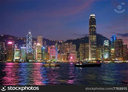 Hong Kong skyline cityscape downtown skyscrapers over Victoria Harbour in the evening illuminated with tourist boat ferries. Hong Kong, China. Hong Kong skyline. Hong Kong, China