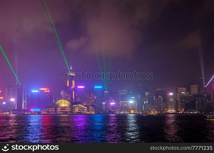 Hong Kong skyline cityscape downtown skyscrapers over Victoria Harbour in the evening illuminated with lasers with tourist boat and ferries . Hong Kong, China. Hong Kong skyline. Hong Kong, China