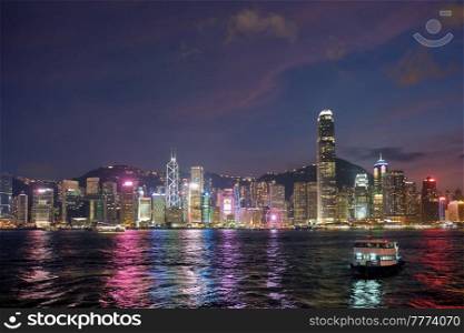 Hong Kong skyline cityscape downtown skyscrapers over Victoria Harbour in the evening illuminated with tourist boat ferries . Hong Kong, China. Hong Kong skyline. Hong Kong, China