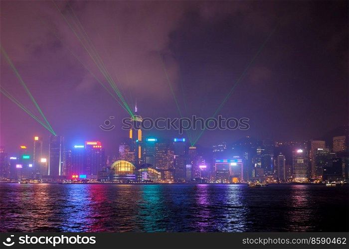 Hong Kong skyline cityscape downtown skyscrapers over Victoria Harbour in the evening illuminated with lasers with tourist boat ferries . Hong Kong, China. Hong Kong skyline. Hong Kong, China