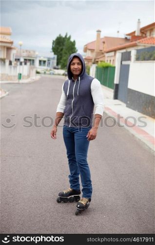Hooded afroamerican guy with skates on the street with a wall background