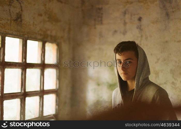 Hooded teenage boy in an abandoned house illuminated by a window