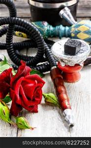 Hookah and red rose. Smoking Turkish hookah filled with tobacco with the taste of roses