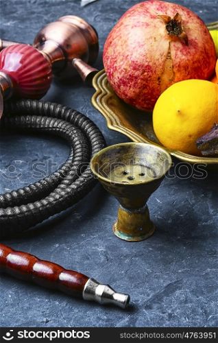 Hookah with taste of tropical fruits. Eastern smoking hookah and dish with pomegranate and lime
