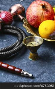 Hookah with taste of tropical fruits. Eastern smoking hookah and dish with pomegranate and lime