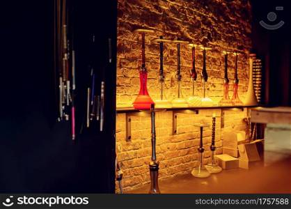 Hookahs with glass bottles at the brick wall, nobody. Shisha bar equipment, traditional smoke culture, tobacco aroma for relaxation. Hookahs with glass bottles, shisha bar