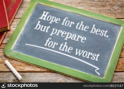Hope for the best but prepare for the worst - advice on a slate blackboard with a white chalk and a stack of books against rustic wooden table