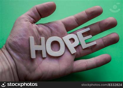         hope word with wooden letters on the green background