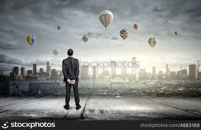 Hopeful businessman. Rear view of businessman looking at aerostats flying above city