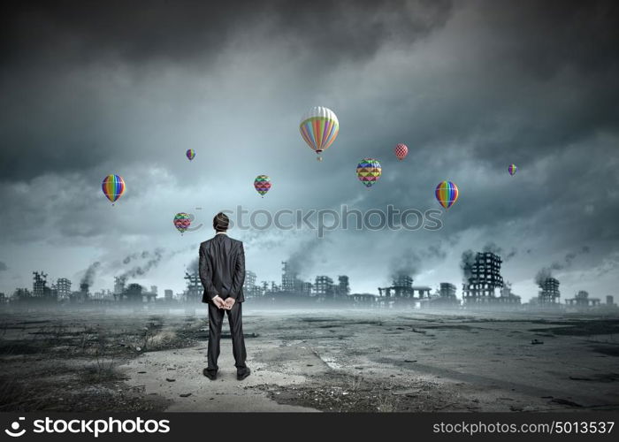 Hopeful businessman. Rear view of businessman looking at aerostats flying above city