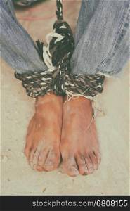 hopeless man feet tied together with rope, human trafficking