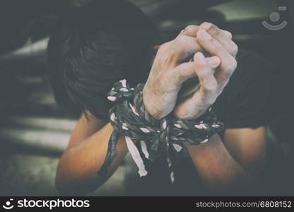 hopeless man hands tied together with rope, human trafficking