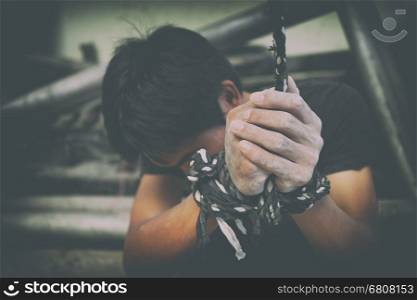 hopeless man hands tied together with rope, human trafficking
