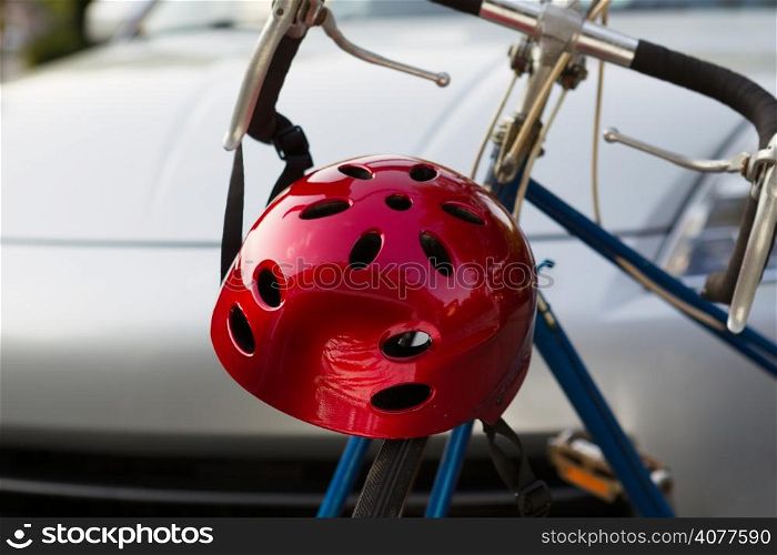 Horizontal closeup image of bike helmet and bicycle in front of blurred out car