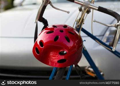 Horizontal closeup image of bike helmet and bicycle in front of blurred out car