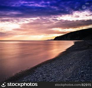 Horizontal dramatic sunset on stony beach background backdrop