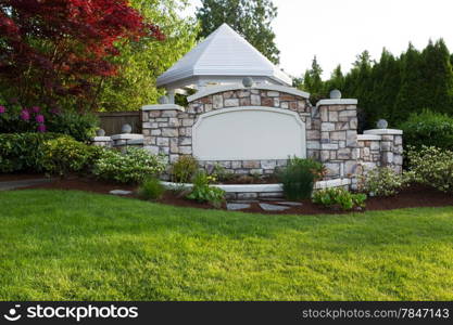 Horizontal evening front view photo of a new white pavilion surround by evergreens, Japanese Red Maple tree and rhododendron flowers in full bloom