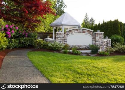 Horizontal evening photo of pathway leading to new white pavilion surrounded by evergreens, Japanese Red Maple tree, plush green grass and rhododendron flowers in full bloom