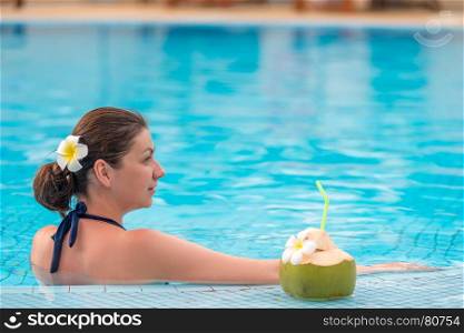 horizontal frame - portrait of a girl in a pool with a coconut