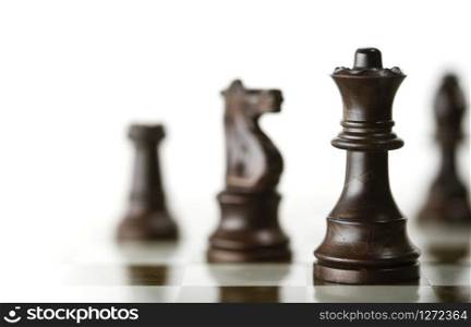 Horizontal image of a chess game with focus on the queen and a blurry pieces over white background, Copy space on the left side. Concept of corporate strategic management or planning or business intelligence.. Chess Game over White Background