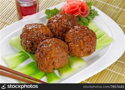 Horizontal image of large freshly cooked meatballs and vegetables with a glass of red wine