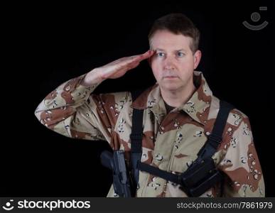 Horizontal image of military male soldier, head gear removed, saluting while armed with black background.