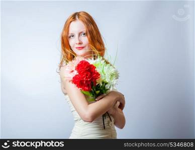 Horizontal image of redhead with bunch of flowers in studio on white. She looking at camera