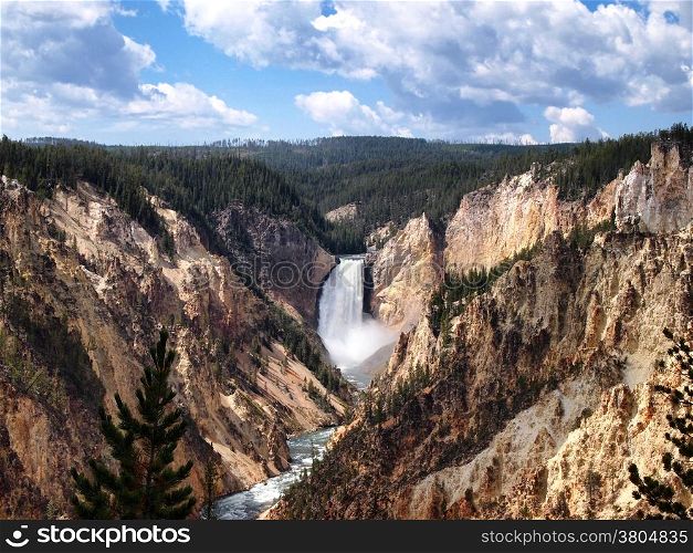 Horizontal image of Yellowstone canyon falls during a beautiful summer day surrounded by pine trees and blue sky with clouds