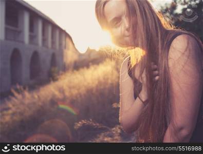 Horizontal image of young blond women smiling and having evening plesure against gold sunset light. Autumn time. Backlit. Cute young lady outdoors rejoice of warm weather fall