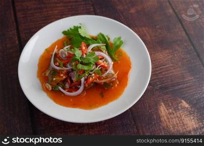 Horizontal image the Spicy salad of sardine with tomato sauce in white dish on wooden table, mixed with herb and lemonade, copy space