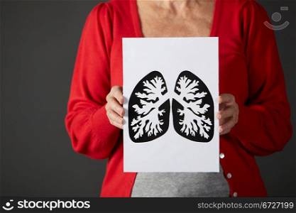 horizontal,indoors,studio shot,black background,holding,drawing,ink,lungs,respiratory,pulmonary,health,disease,illness,sickness,unhealthy,casual clothing,mid section,front view,shadow,people,one person,female,woman,caucasian,adult,60s,sixties,senior,older,mature,retired,retirement,cropped