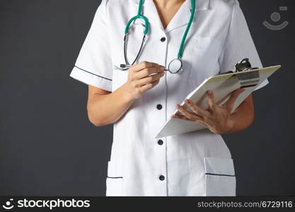 horizontal,indoors,studio shot,black background,nurse,stethoscope,clipboard,pen,writing,health service,hospital,medical,healthcare,uniform,white,mid section,front view,people,one person,female,woman,caucasian,adult,30s,thirties,cropped,american,usa