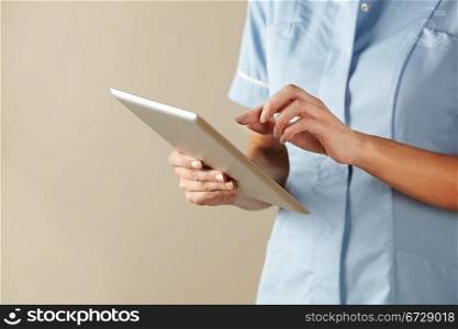horizontal,indoors,studio shot,white background,nurse,computer,tablet,technology,health service,hospital,nhs,medical,healthcare,uniformblue,standing,mid section,copy space,people,one person,female,woman,caucasian,adult,30s,thirties,cropped,british,english,uk