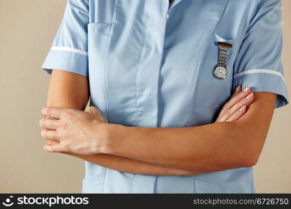 horizontal,indoors,studio shot,white background,nurse,health service,hospital,nhs,medical,healthcare,uniform,blue,standing,arms folded,watch,mid section,people,one person,female,woman,caucasian,adult,30s,thirties,cropped,british,english,uk