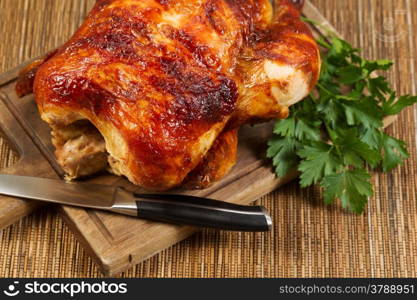 Horizontal photo of a freshly oven roasted Whole Chicken on traditional rustic cutting board with knife and parsley on side