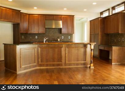 Horizontal photo of a new residential kitchen with stone counter tops, cherry cabinets and hardwood floors