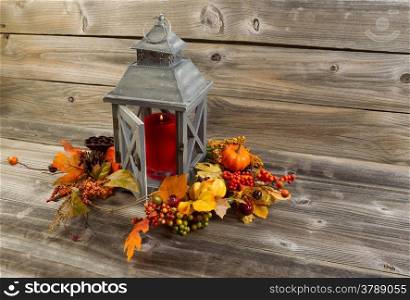 Horizontal photo of an old Asian design lantern with red candle burning inside on rustic wood