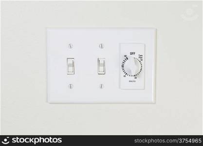 Horizontal photo of bathroom fan and light switches with timer on wall