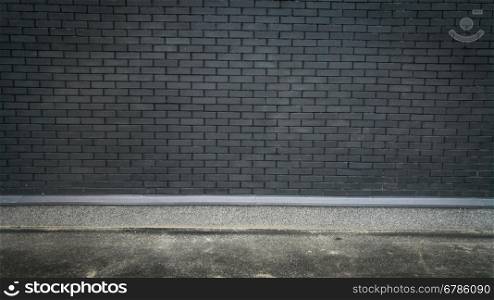 Horizontal photo of concrete floor and black brick wall. Place for text