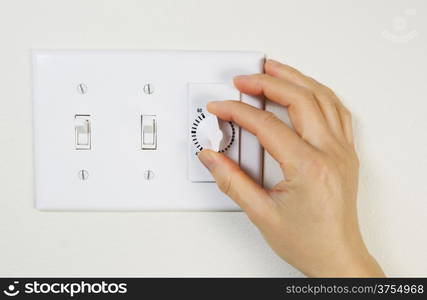 Horizontal photo of female hand adjusting bathroom fan timer