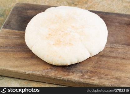 Horizontal photo of fresh pita bread on old wooden cutting board with knife