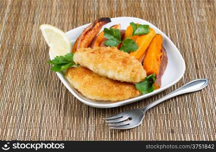 Horizontal photo of fried golden breaded coated fish and yams on white plate