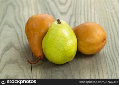 Horizontal photo of one Green and two brown pears on aged wood